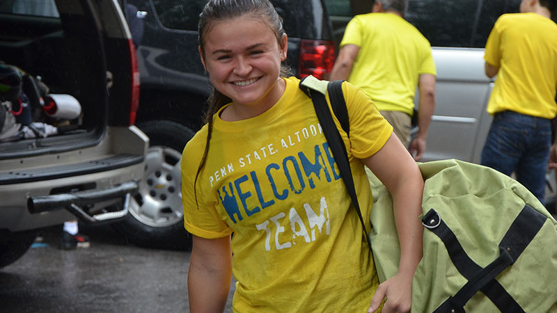 A student volunteer carries supplies to a first-year student's room