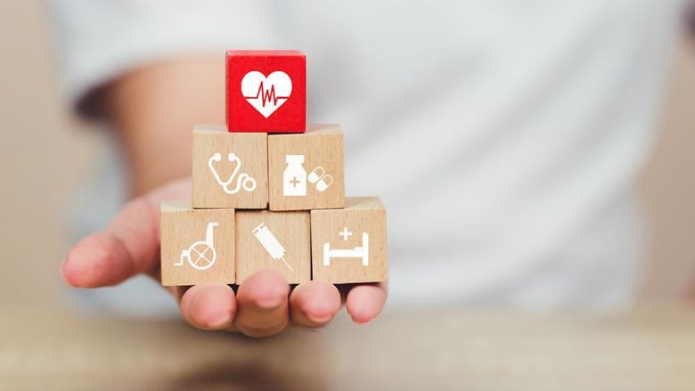A hand holding building blocks representing different aspects of healthcare