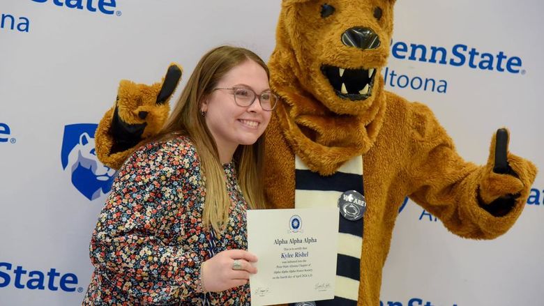 Psychology major Kylee Rishel poses with her certificate and the Nittany Lion after the induction ceremony.
