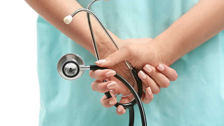 a close-up of a nurse holding a stethoscope behind her back