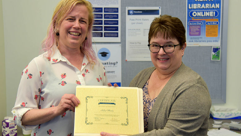 Lori Lysiak, reference and instruction librarian, presents Kelly Munly with the OAER Champion Award for her lightning talk at the campus's first Open and Affordable Showcase.