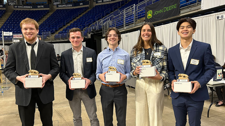 Five students, Dale Miller, Kieran Meehan, Taylor Casavant, Sydney McKernan and James Fong, stand in a row, all holding award statues of the Penn State Nittany Lion