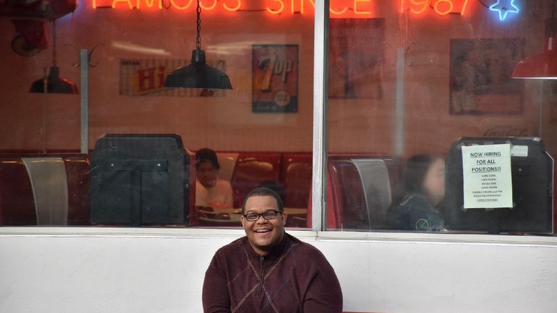 Photograph of man posing in front of diner