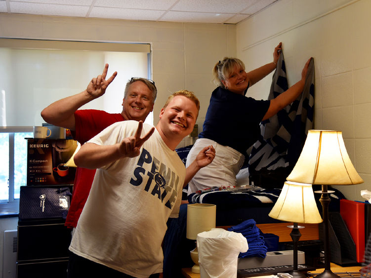 A first-year student poses in his residence hall room with his parents