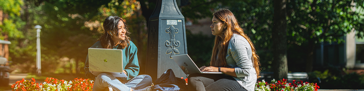 Two female students sitting near the railroad clock on the Penn State Altoona campus