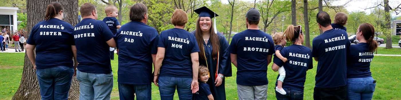 A recent graduate named Rachel poses with family, all of whom are wearing t-shirts with her name on them.