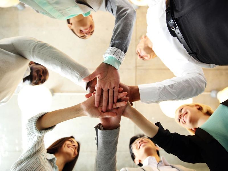 Six young entrepreneurs putting there hands together in the center of a circle