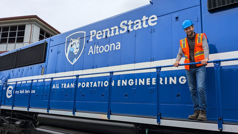 Penn State Altoona alumnus Jason Levinn poses for a photo on the PSU 2020 locomotive.