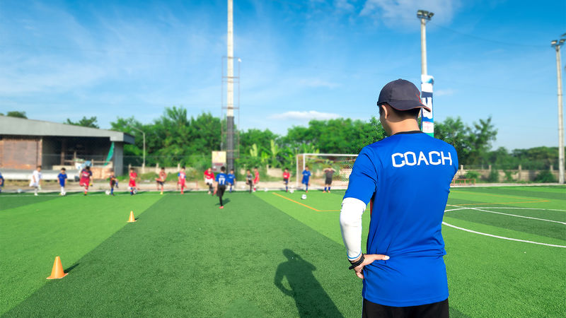A coach and athletes on the field