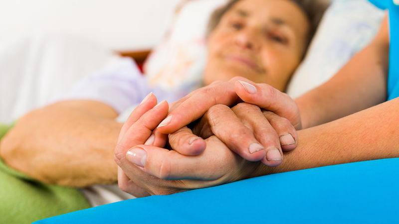 A nurse holding a patient's hand