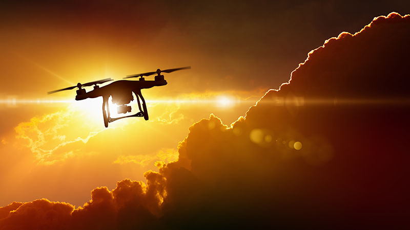 A drone flying away at sunset