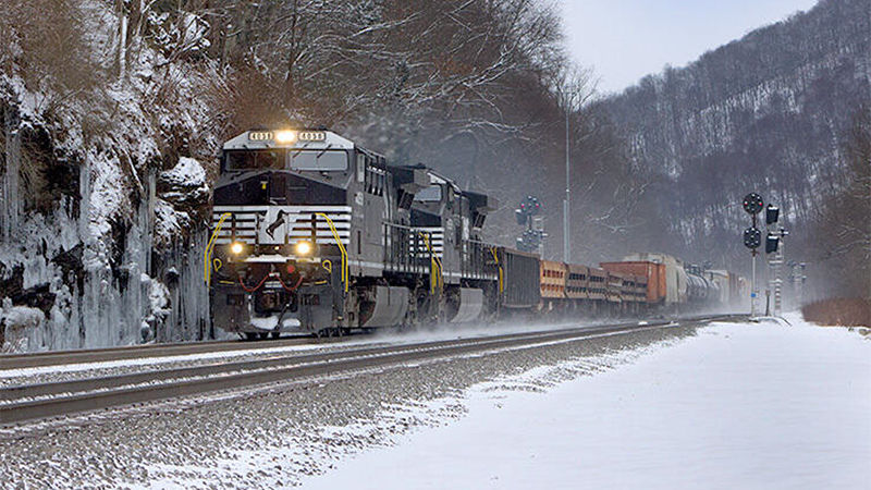 A photo of a locomotive on a track surrounded by snowy mountains
