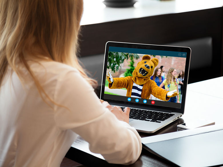 A woman having a virtual visit with the Nittany Lion on her laptop