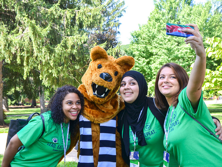 Three first-year students taking a selfie with the Nittany Lion