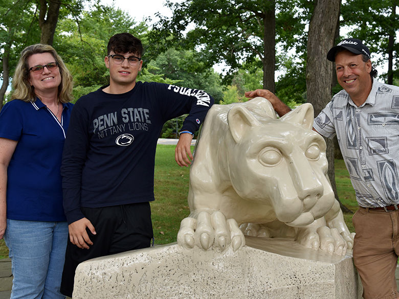 A first-year student poses with his parents in front of the Lion Shrine