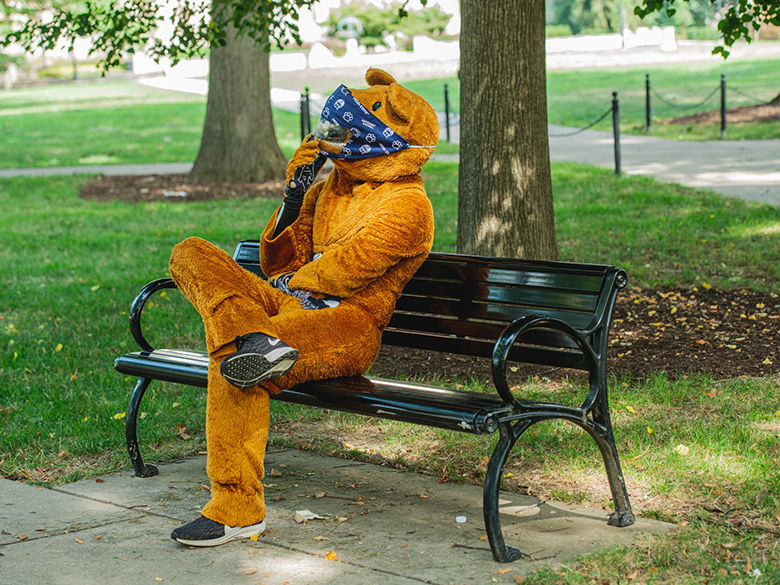 The Nittany Lion mascot sitting on a bench wearing a mask