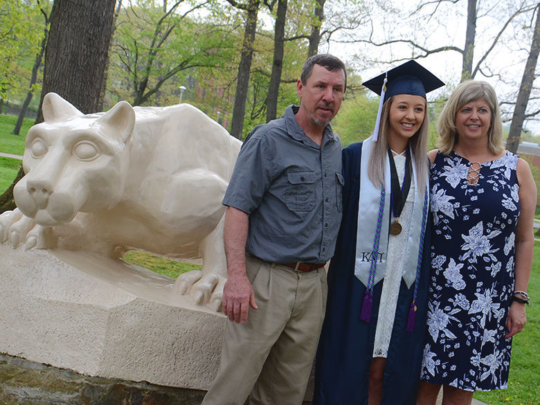 A recent graduate poses with her parents in front of the Lion Shrine at Penn State Altoona