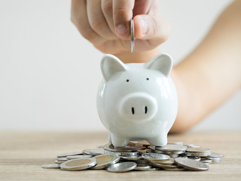 A piggy bank with a hand dropping coins inside