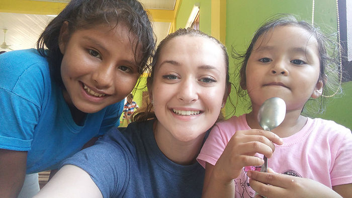 Kelsey Brumbaugh poses with two girls at Andrea’s Home of Hope and Joy in the cafeteria