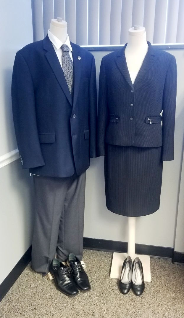 A man's and woman's suit on two dummies