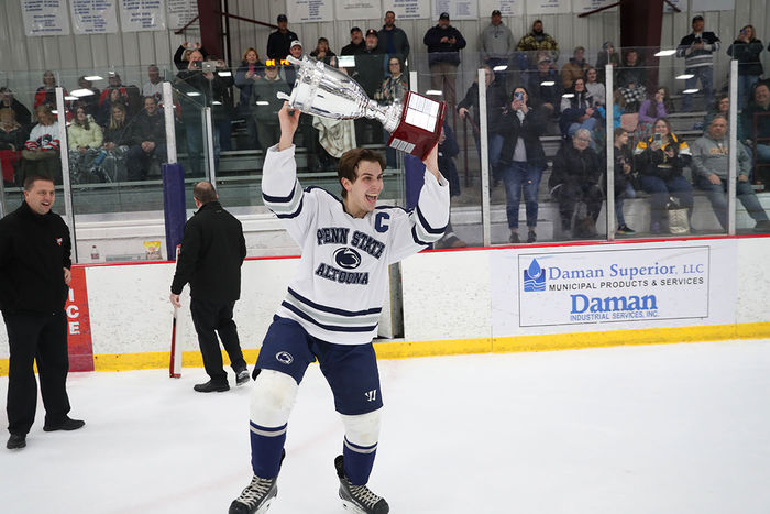 Team captain Christian Strang raises the College Hockey East trophy after the championship game against Robert Morris University in February. 