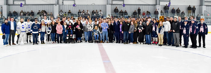 Players from both hockey teams, event organizers, and honorees pose for a group photo.