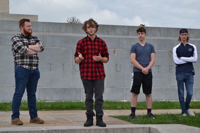Four students standing in front of a wall