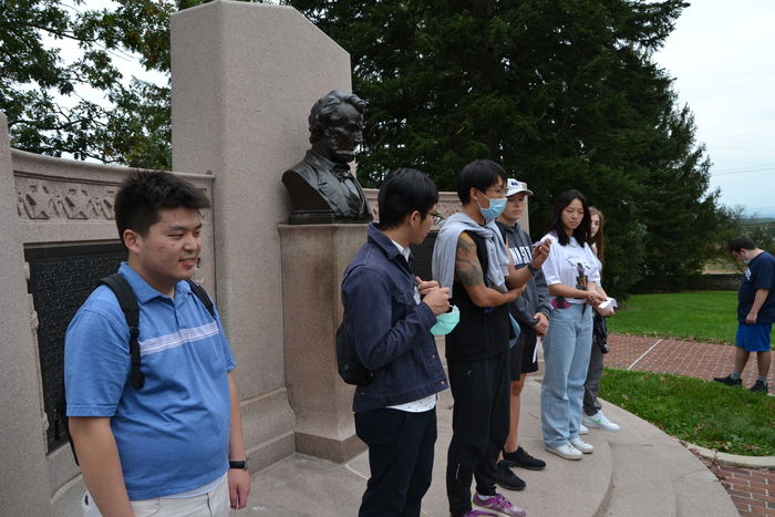 International and domestic students standing in front of a memorial
