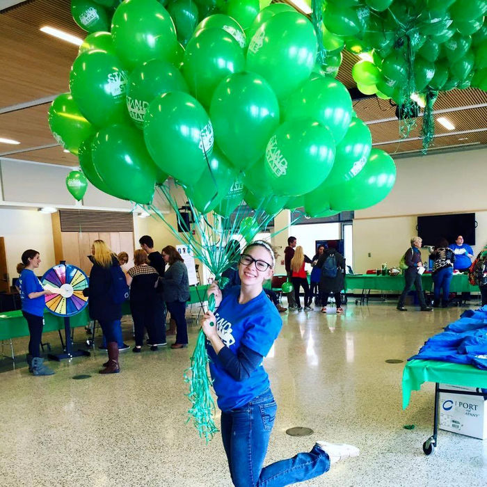 Gabrielle Davidson poses with a cluster of balloons at a Stand for State bystander intervention event.