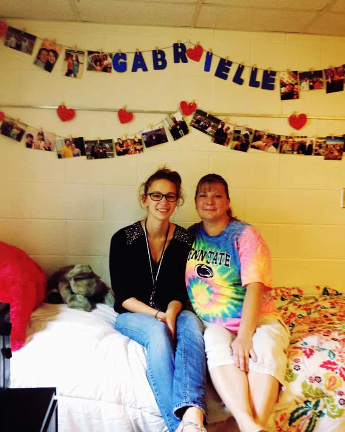 Gabrielle Davidson sits with her mother on the bed in her residence hall room.