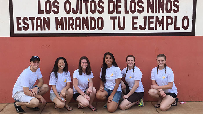 The students pose in their Project International Impact Bolivia shirts underneath this quote which translates to The eyes of the children are watching your example.