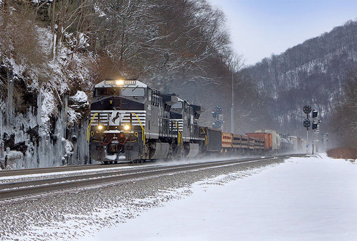 A photo of a locomotive on a track surrounded by snowy mountains