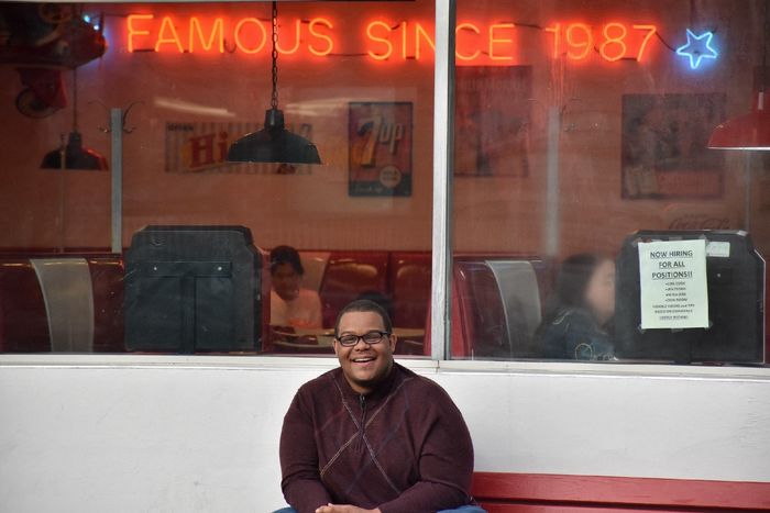 Photograph of man posing in front of diner