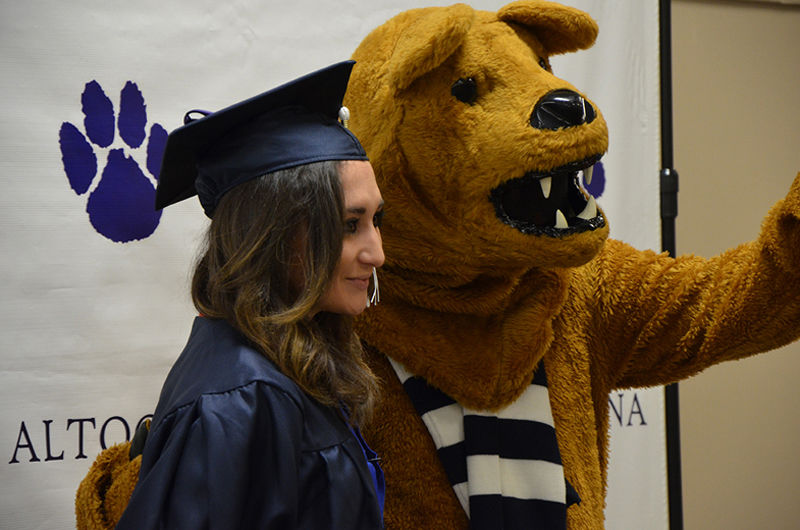 A Graduate poses with the Nittany Lion at Fall 2016 Commencement