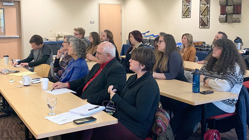 Faculty, students, and family members listen to presentations by senior English students