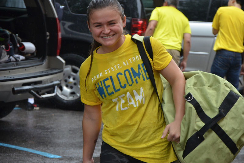 A student volunteer carries supplies to a first-year student's room