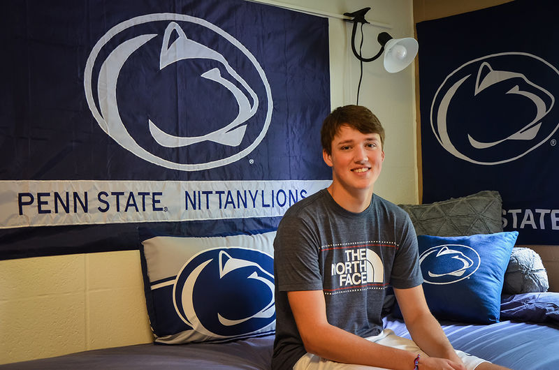 A first year student poses in his residence hall room