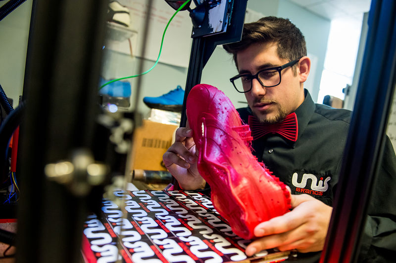A photo of Nicholas Unis inspecting a prototype of his 3D printed shoe