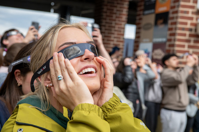 Woman wearing eclipse glasses looking up