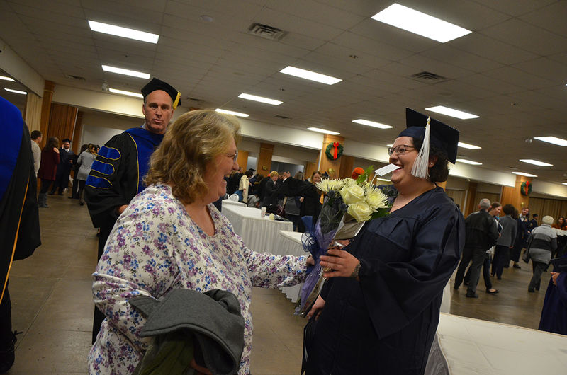 A proud family member presents flowers to a graduate at the Fall 2017 Commencement ceremony