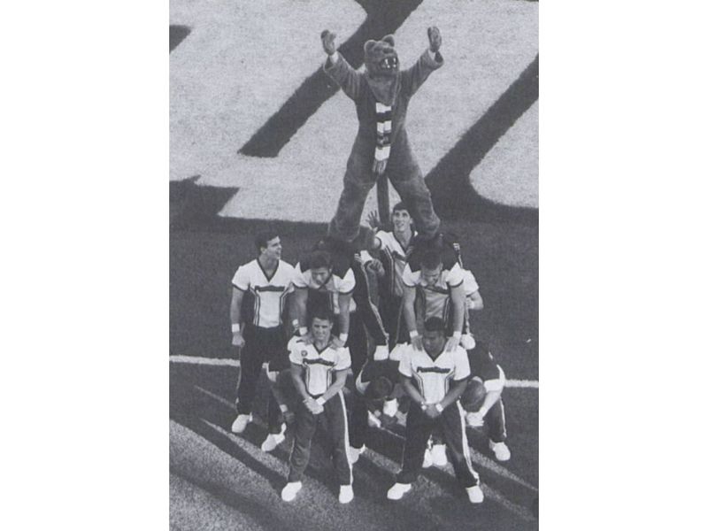 A group of male cheerleaders holds the Nittany Lion on the sideline of a football game in 1998