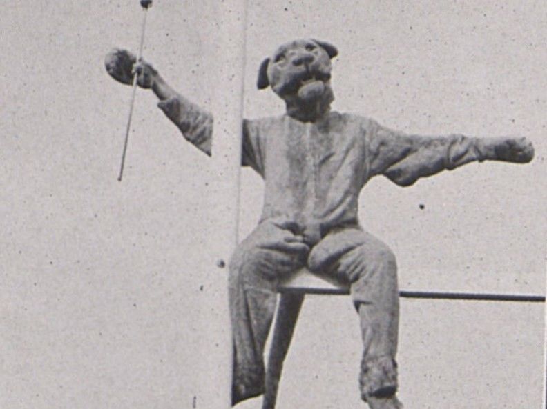 The Nittany Lion sits on top of a goal post, holding a baton, in 1940.