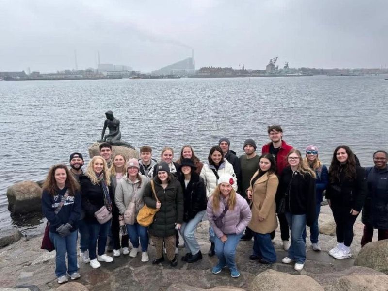 A group of students pose at a waterfront