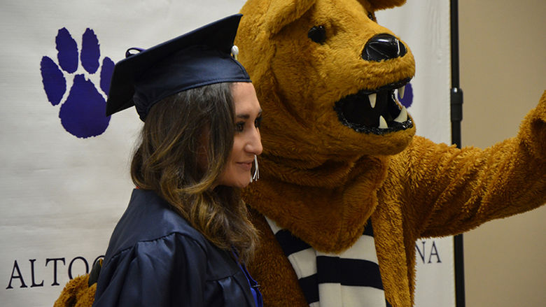 A Graduate poses with the Nittany Lion at Fall 2016 Commencement