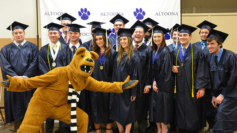 Graduates pose with the Nittany Lion at Fall 2016 Commencement