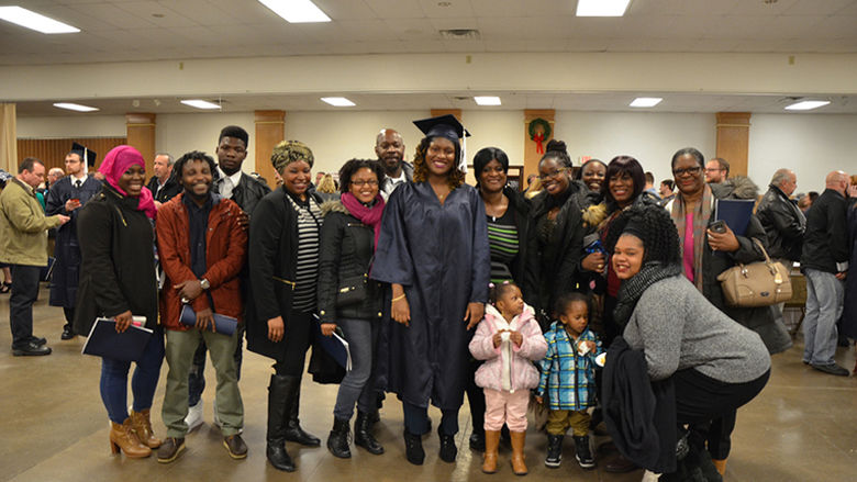 A graduate poses with her family after Fall 2016 Commencement ceremony