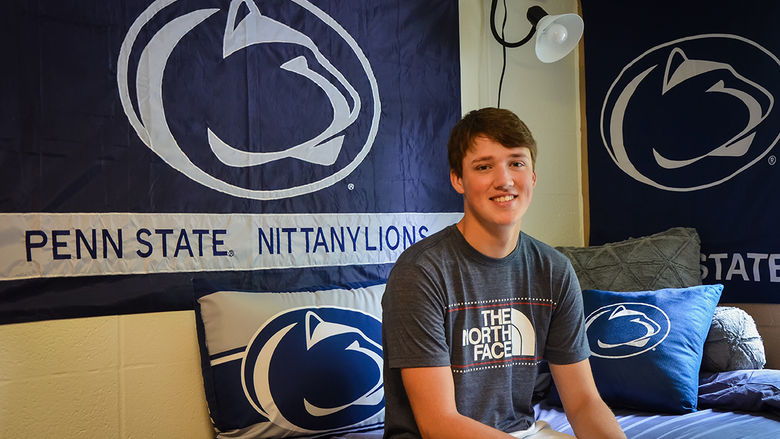 A first year student poses in his residence hall room