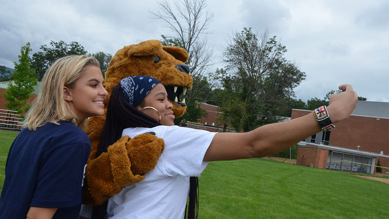 Students pose for a selfie with the Nittany Lion