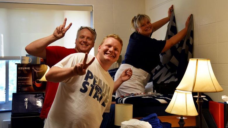 A first-year student poses in his residence hall room with his parents