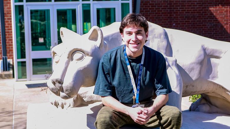Student smiling by the Greater Allegheny Lion Shrine